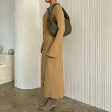 A model wearing a suede recycled vegan leather shoulder bag against a white wall.