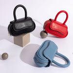 A still image of three oval shaped crossbody handbags with ball props in the background. 