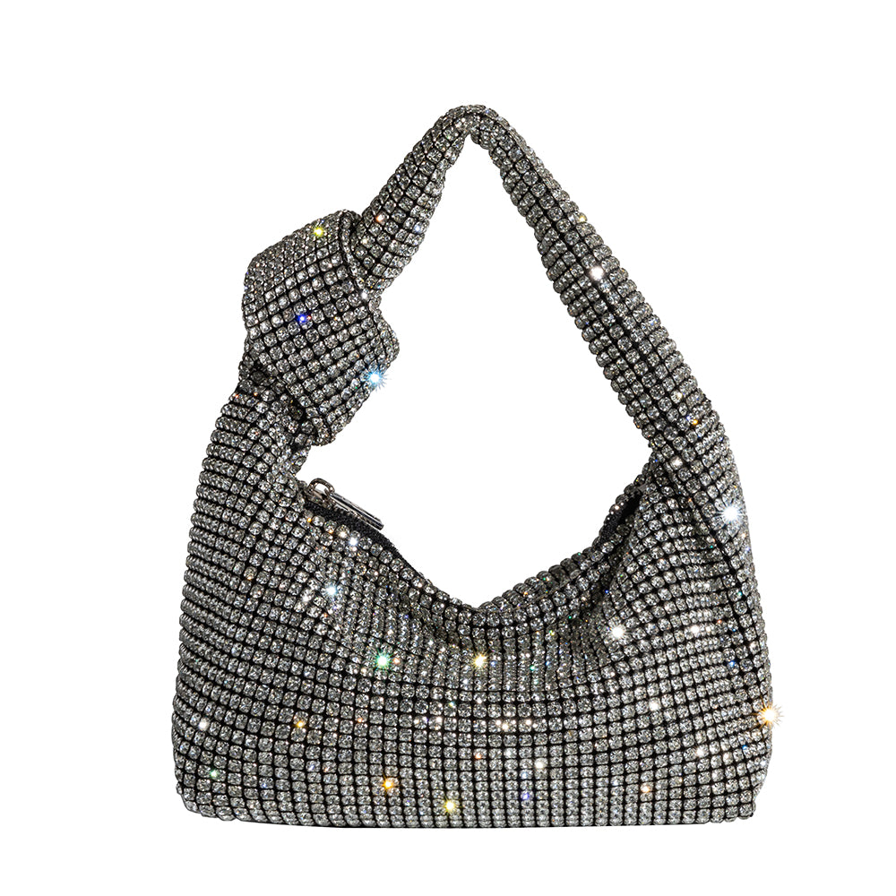 A small silver crystal encrusted silver top handle bag with a knot. 