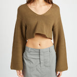 A model wearing a v-neck cropped green sweater against a white background.