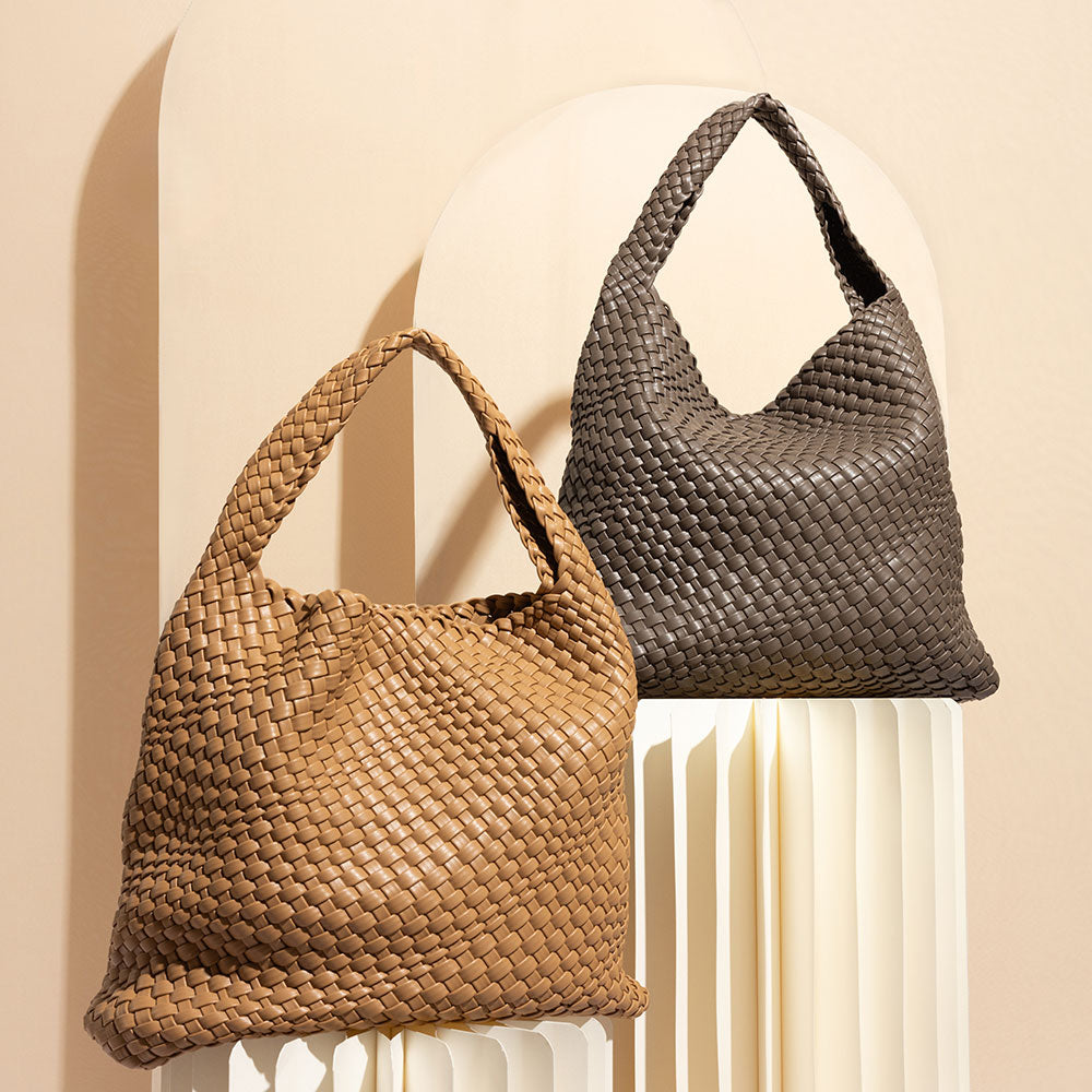 A still image of two large woven vegan leather shoulder bags against a cream wall. 