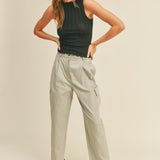A model wearing a beige high rise cargo pant against a tan wall. 