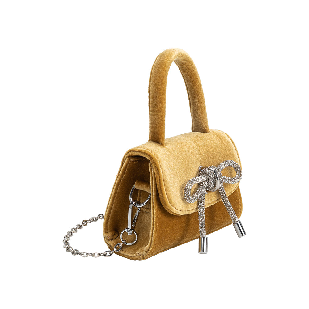 A mini gold velvet top handle bag with a silver encrusted bow.