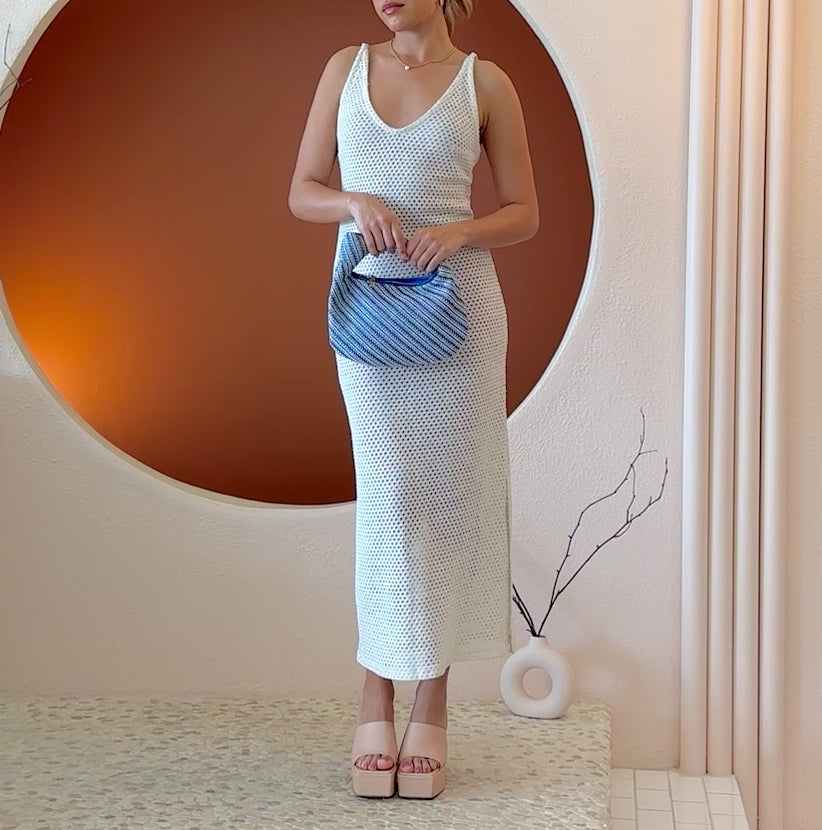 Video of a model wearing a small blue straw top handle bag with a knot handle