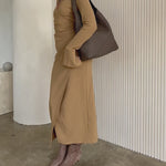 Video of a model wearing a large woven vegan leather bag against a white wall.