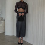 Video of a model wearing a mini velvet vegan leather top handle bag with a silver encrusted handle against a white wall. 