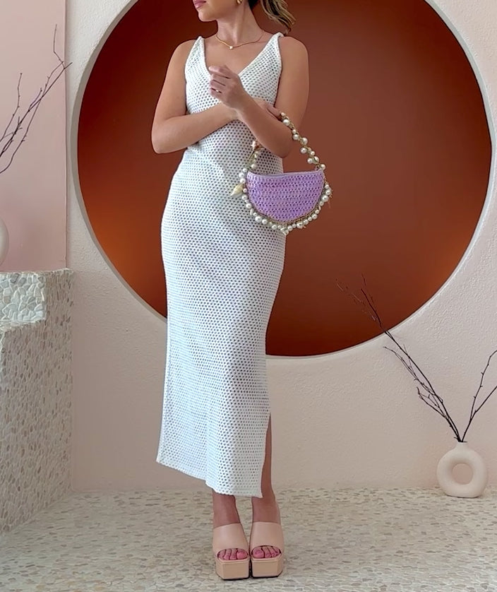 Video of a model wearing a small crochet straw top handle bag with a seashell detail along the handle