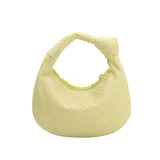 a small yellow straw woven top handle bag with a knot handle