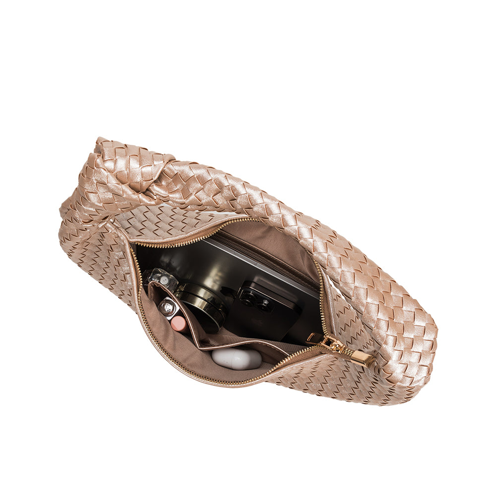 An inside view image of a large woven shoulder bag with a knot handle with a phone, wallet, and makeup inside