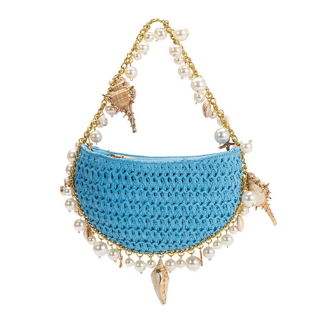 A small blue crochet straw top handle bag with seashell details along the handle.