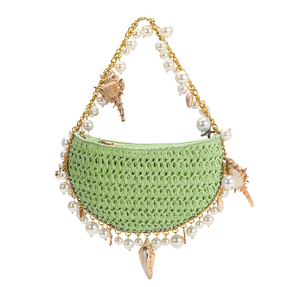 A small lime crochet straw top handle bag with a seashell detail along the handle.