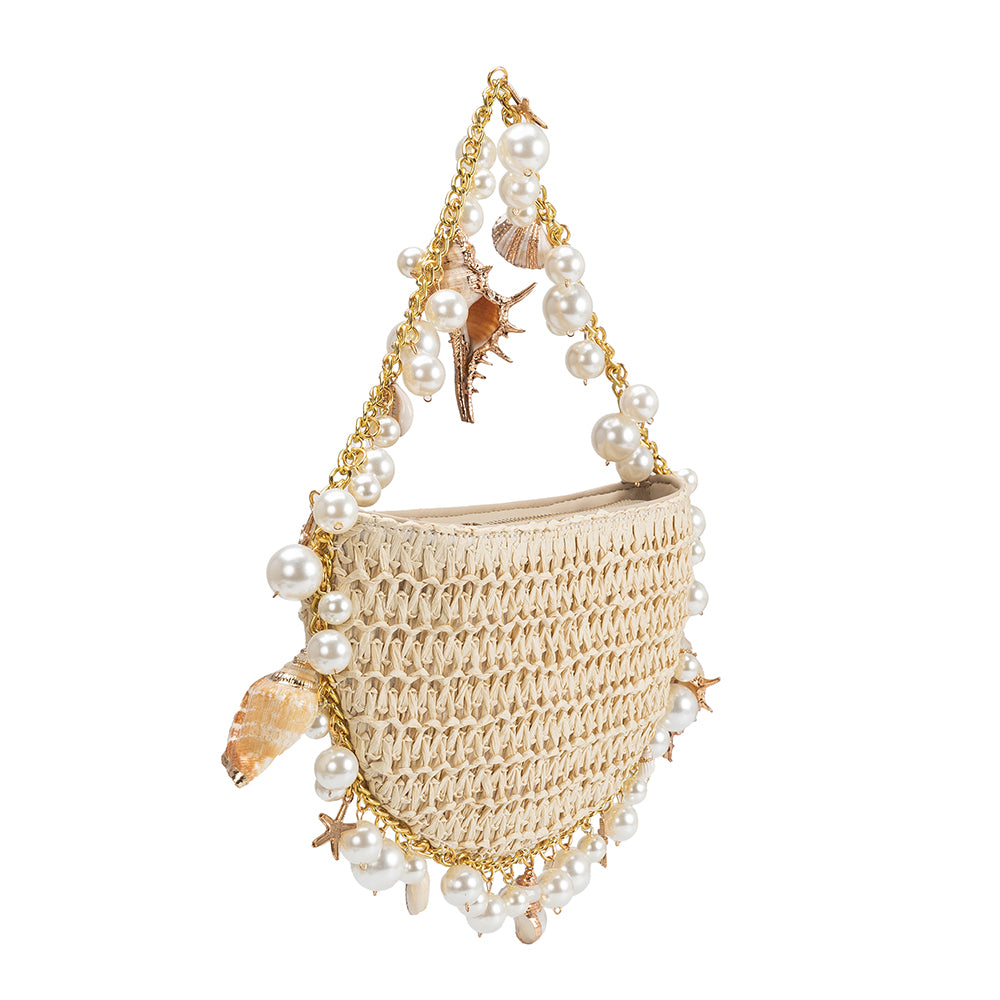 A small natural crochet straw top handle bag with seashell details along the handle
