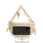An iphone 14 size comparison image for a small crochet straw top handle bag with seashell details along the handle