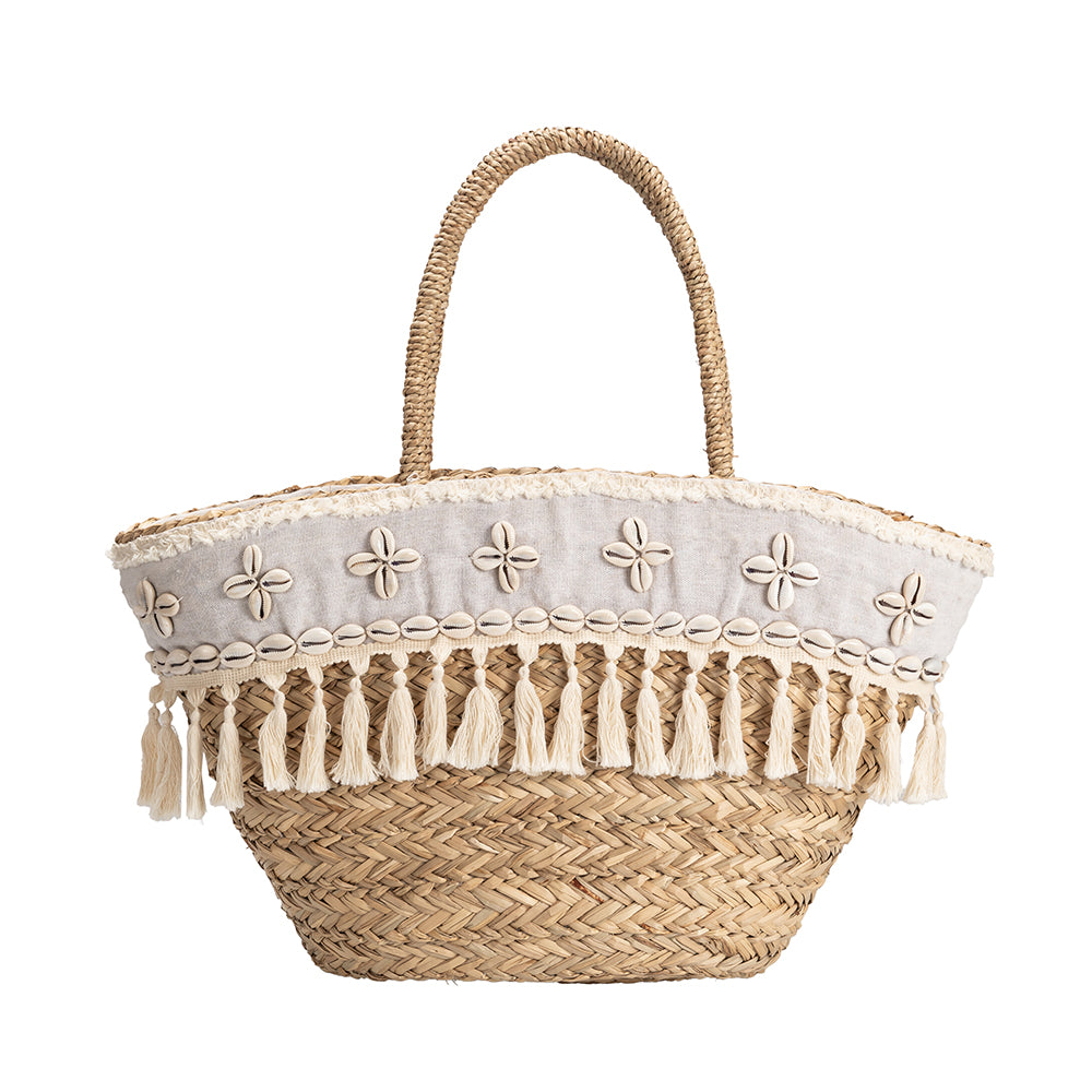 A large straw woven tote bag with seashell details on the front and a drawstring closure.