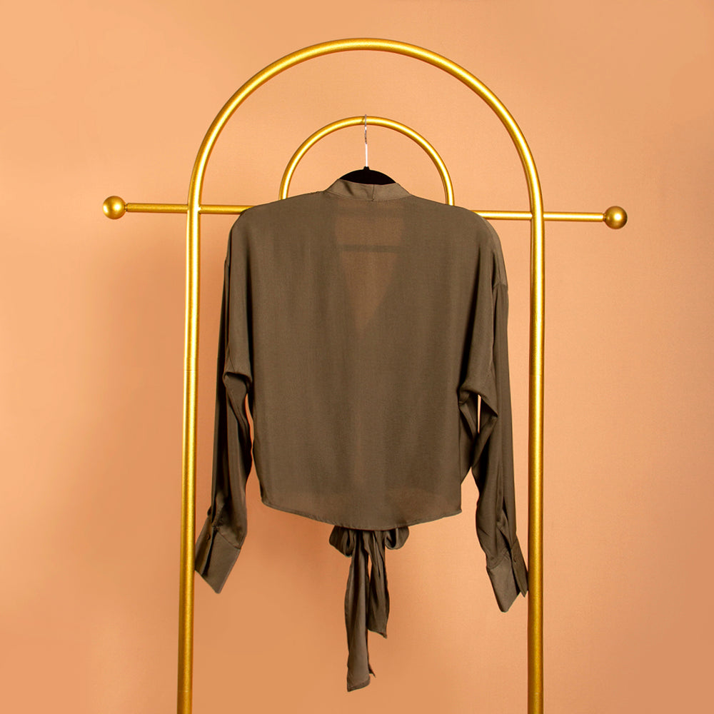 A backside view still image of a green tie front top on a hanger against an orange background.