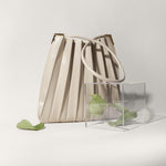 Still photo of a pleated vegan leather shoulder bag with a box of leaves.