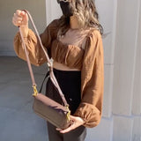 A model wearing a woven top and shrug set outside against a wall. 