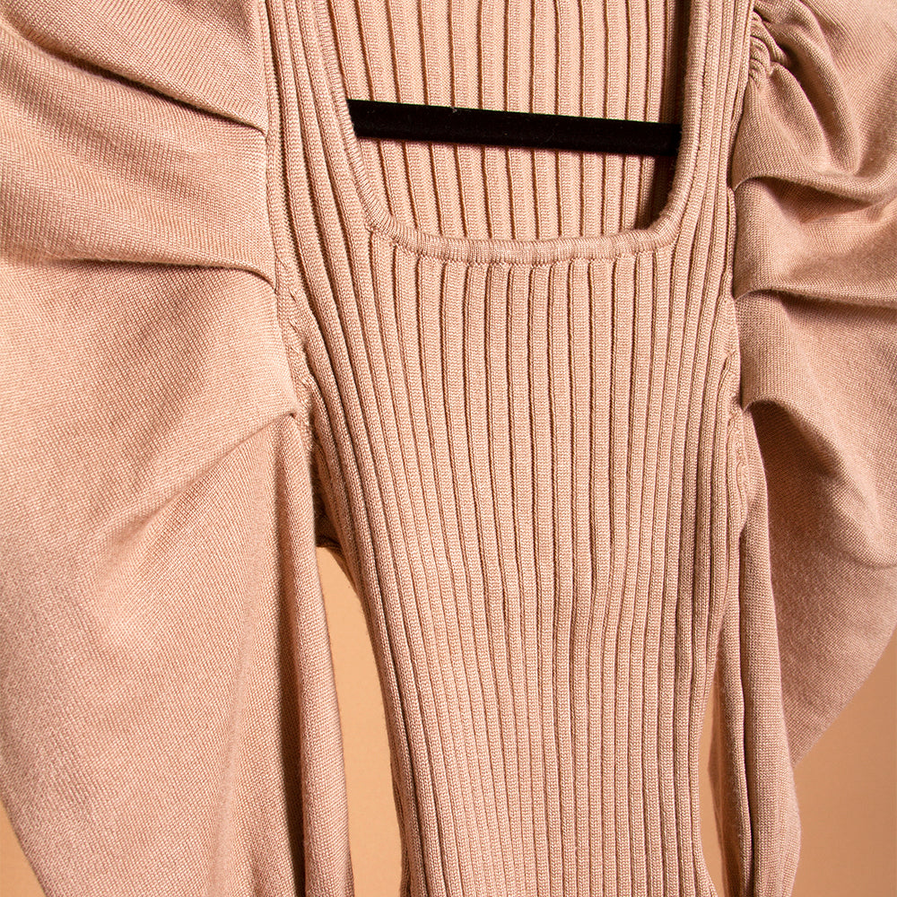 A detail image of a tan puff sleeve knit bodysuit on a hanger. 