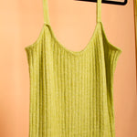 A still detailed image of a green midi rib knit dress on a hanger with an orange background. 