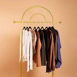 A still image of nine pieces of clothing on hangers against an orange background,