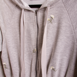 A detail image of a grey terry hooded romper with flower details.