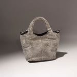 A still image of a small crystal encrusted crossbody bag with a slouchy silhouette against a grey background.