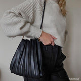 Model wearing a black pleated vegan leather shoulder bag.