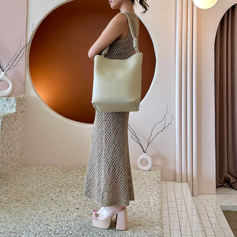 A model wearing a large tote bag with double knotted handle.