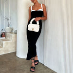 A model holding an ivory knitted crossbody handbag against a white wall.