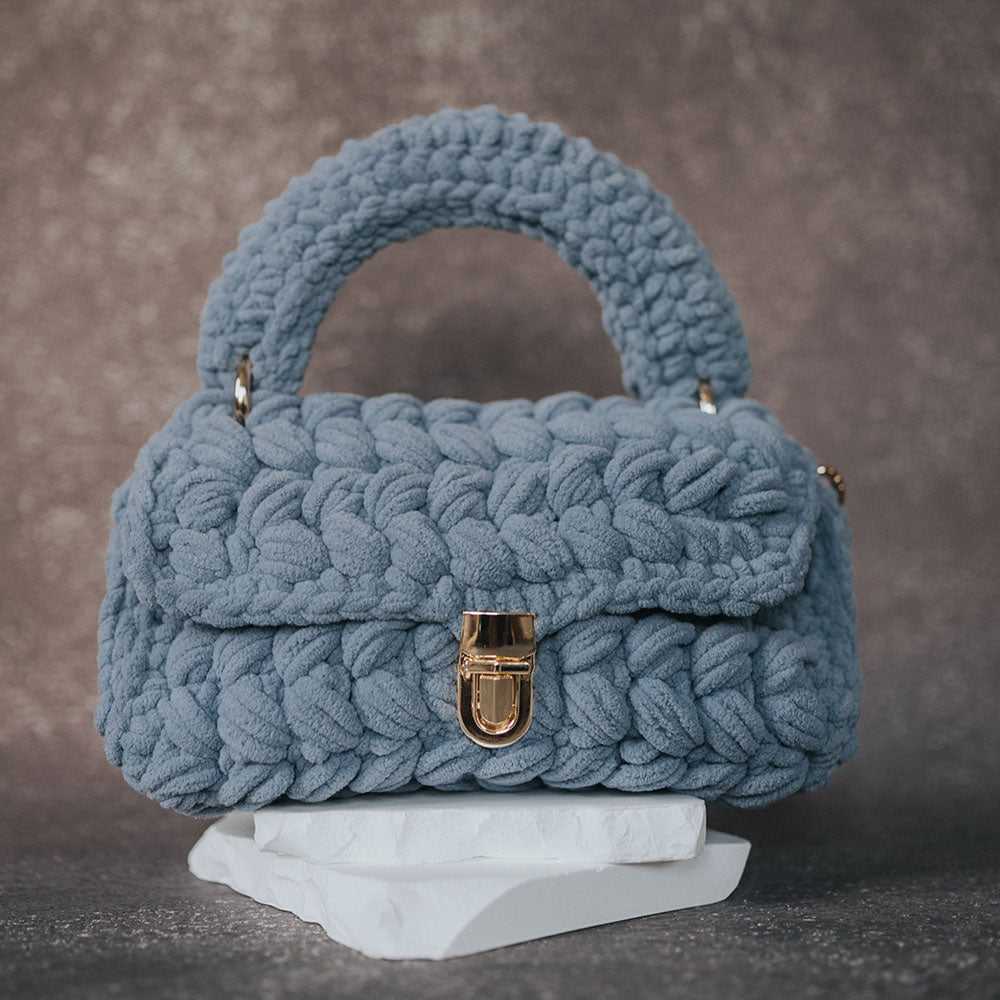 A sky knitted crossbody handbag with gold clasps. 