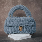 A sky knitted crossbody handbag with gold clasps. 