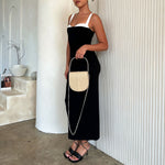 A model holding a ivory vegan leather crossbody handbag with silver handle.
