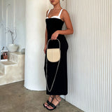 A model holding a nude vegan leather crossbody handbag against a white wall.
