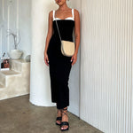 A model wearing a nude vegan leather crossbody handbag against a white wall.