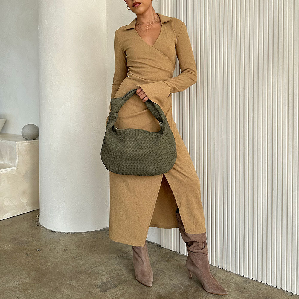 Model wearing a suede recycled vegan leather shoulder bag against a white wall.