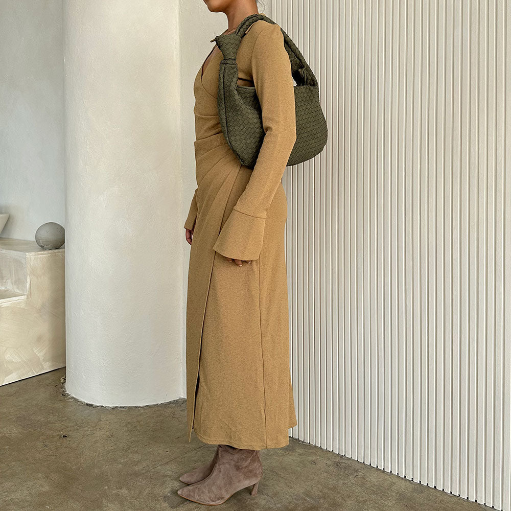 Model wearing a suede recycled vegan leather shoulder bag against a white wall. 
