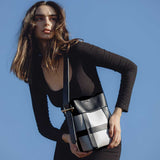 A model wearing a small vegan leather shoulder bag with a zip pouch inside.