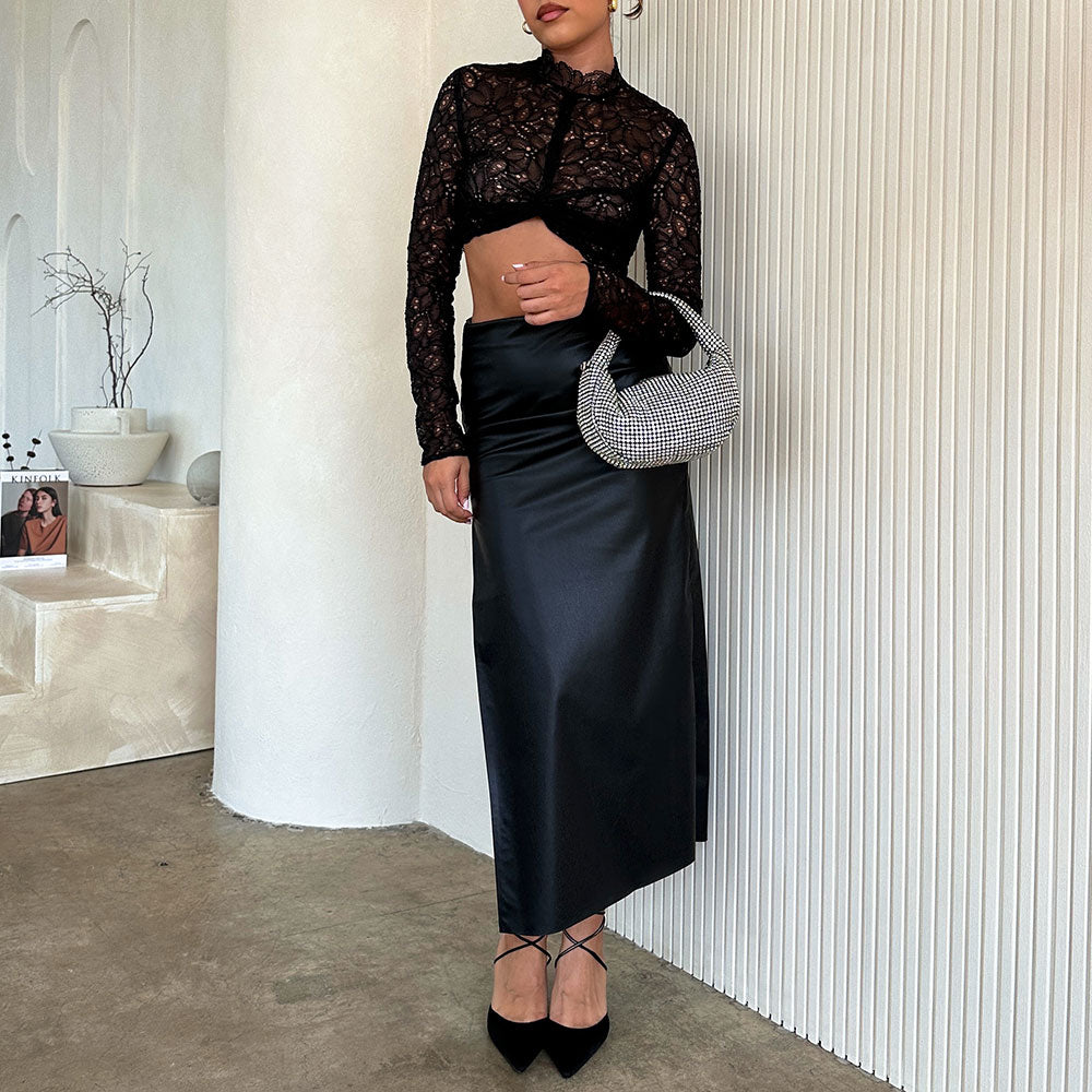 A model wearing a small crystal encrusted crossbody bag against a white wall. 