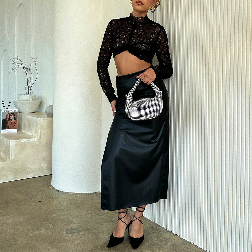 a model wearing a small crystal encrusted crossbody bag against a white wall. 