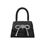 A mini black velvet top handle bag with a silver encrusted bow.