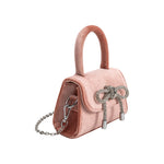 A mini blush velvet top handle bag with a silver encrusted bow.
