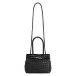 A black hand woven vegan leather crossbody bag with curved handle. 