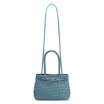 A sky hand woven vegan leather crossbody bag with a curved handle. 