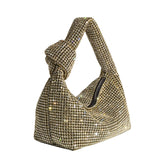 A small gold crystal encrusted top handle bag with a knot.