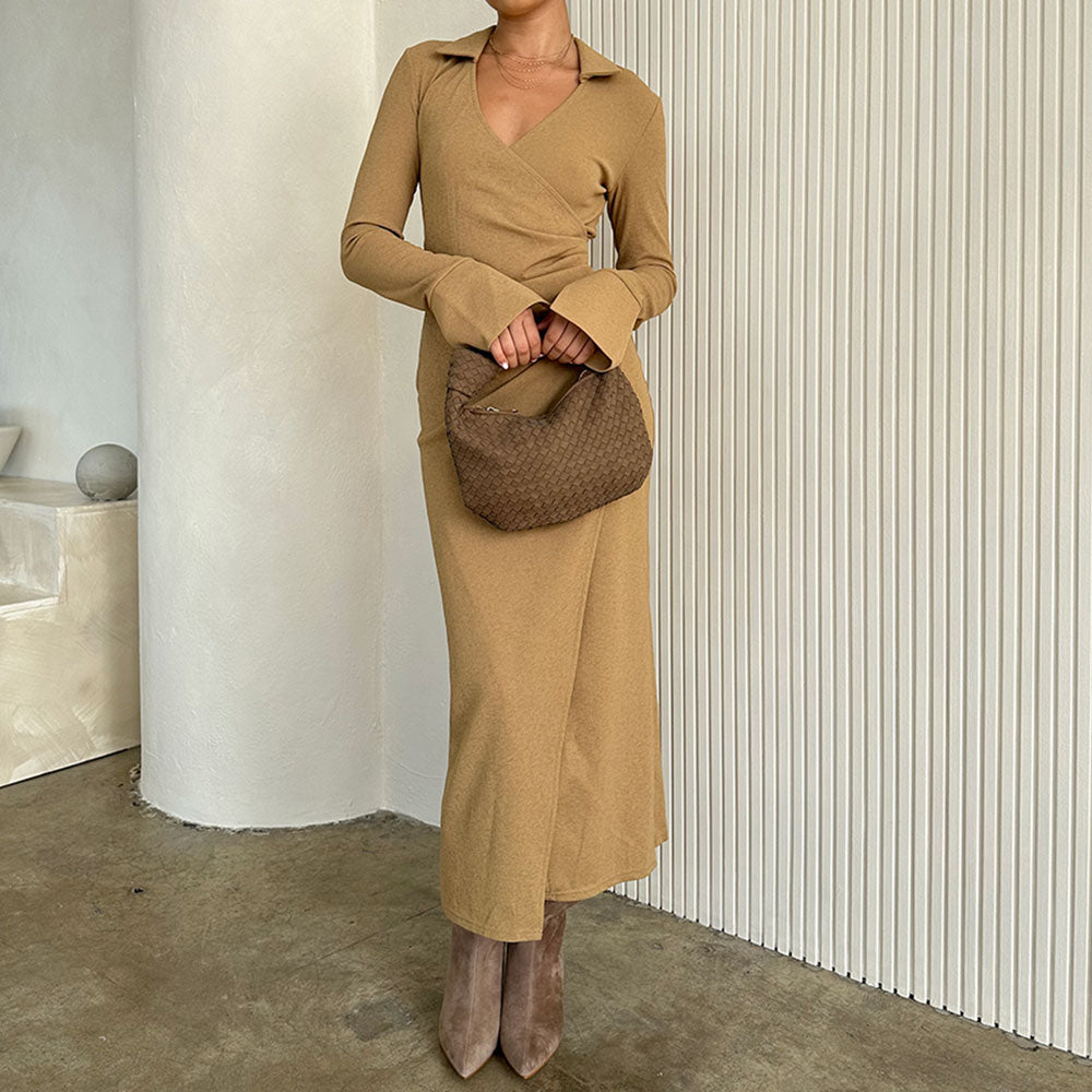 A model holding a suede recycled vegan leather top handle bag with a knot. 