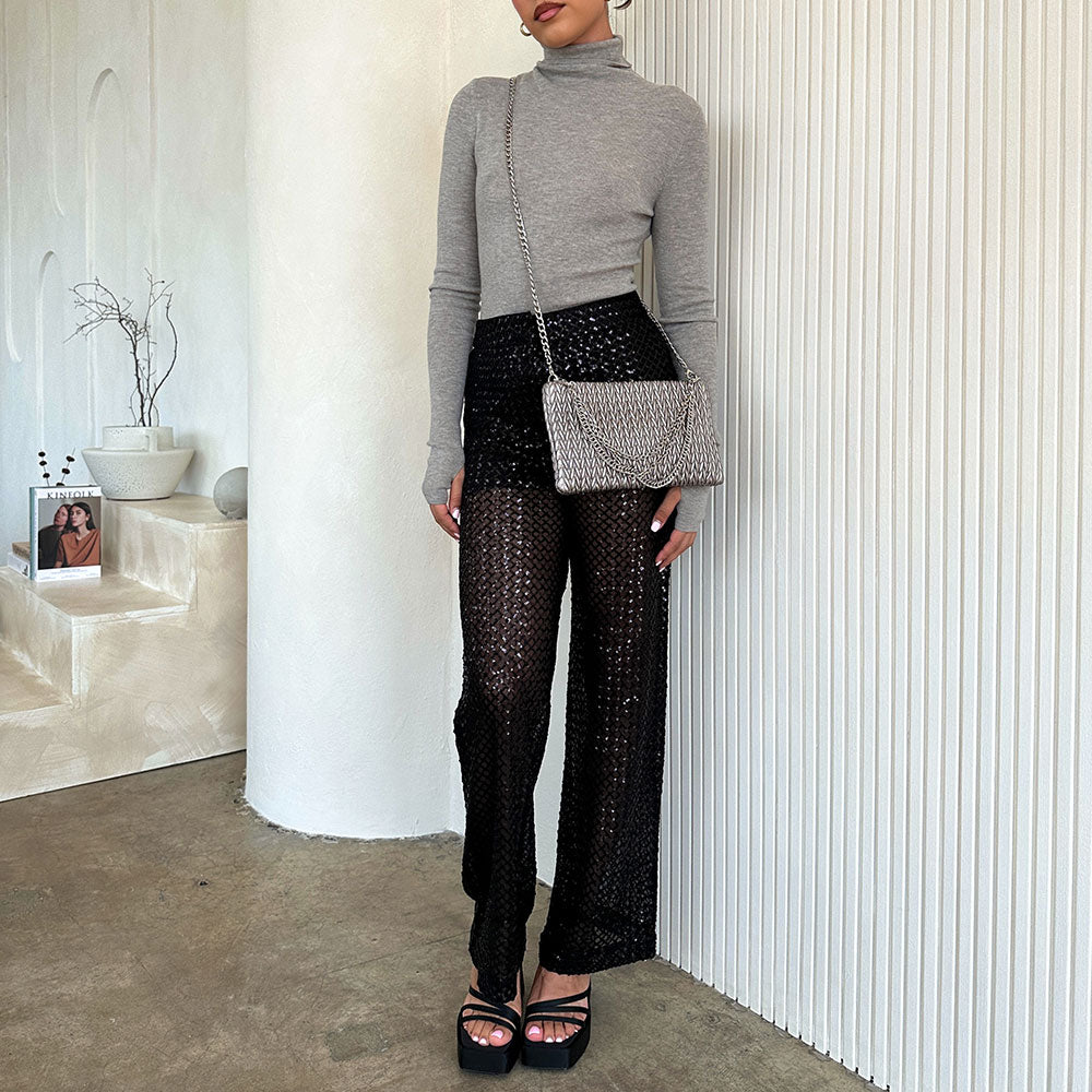 A model wearing a small quilted pattern crossbody clutch against a white wall. 