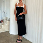 A model holding a small recycled vegan leather crossbody bag against a white wall. 