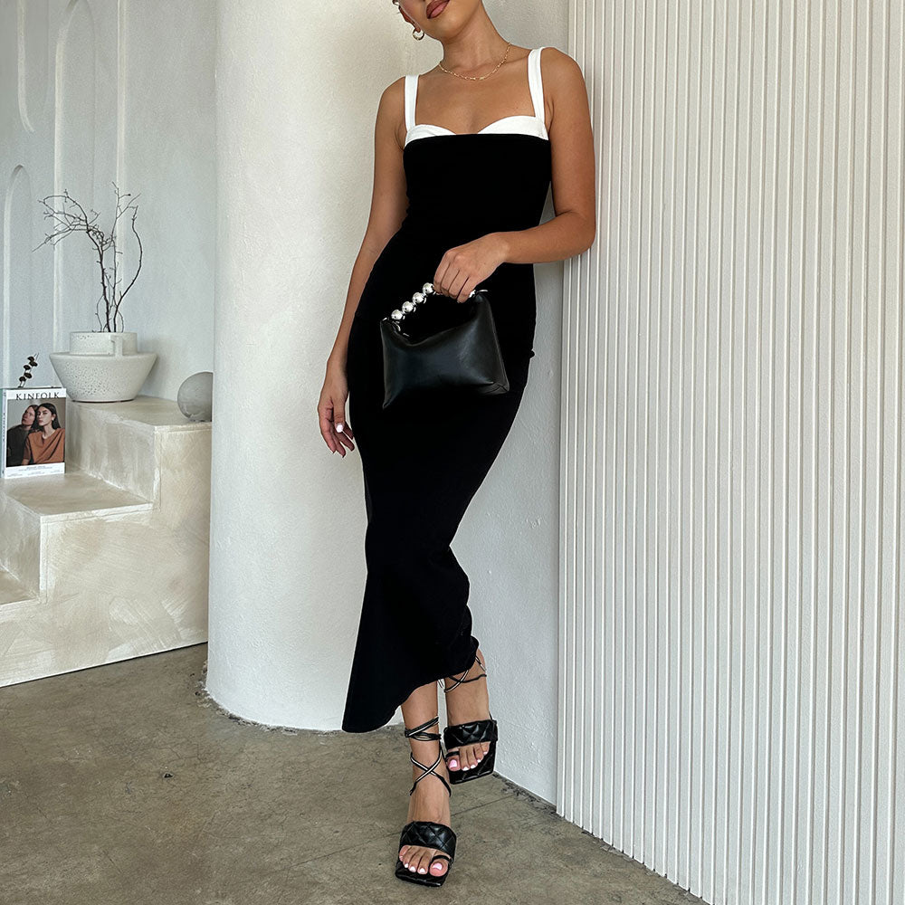 A model holding a small recycled vegan leather crossbody bag against a white wall. 