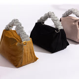 A still image of three medium velvet top handle bags against a white background. 
