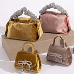 A still image of four different velvet handbags with silver encrusted handles and bows.